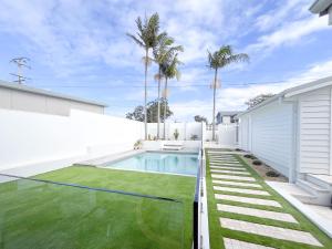 a backyard with a swimming pool and grass at Riva House in Summerland Point