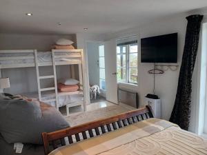 ein Schlafzimmer mit zwei Etagenbetten und einem Fernseher in der Unterkunft The Harbour Masters Cottage in Tairua