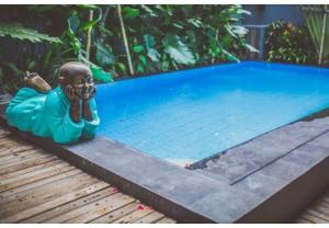 a statue of a mermaid next to a swimming pool at Balissimo Suites Seminyak by Betterplace in Seminyak +21 photos