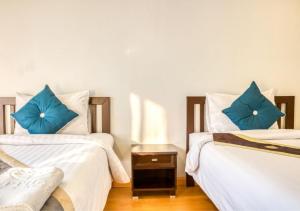 two beds with blue pillows in a room at Kiatthada Resort in Bangkok