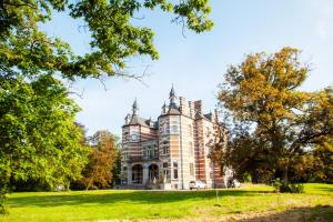an old house on a grassy field with trees at Chateau Morreau in Péruwelz