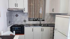 a kitchen with white cabinets and a sink and a microwave at Toula's Garden-View Apartment 3 in Moúdhros +4 photos