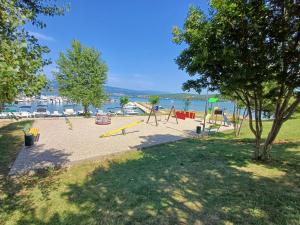 an empty playground with swings and trees and the water at 16 Čižići in Čižići