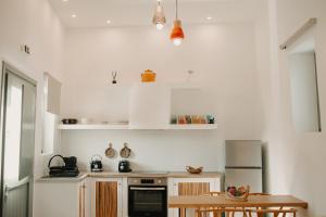 a kitchen with white cabinets and a wooden table at Venue Villas - Folegandros in Áno Meriá