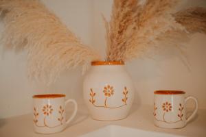 two white mugs sitting next to some feathers at Venue Villas - Folegandros in Áno Meriá