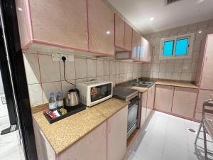 a small kitchen with pink cabinets and a microwave at الذهبية راحتي in Al Thybiyah