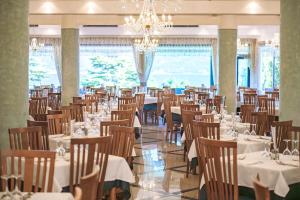 a dining room with tables and chairs and a chandelier at Hotel Garda Bellevue in Limone sul Garda