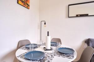 a white dining room table with blue plates on it at Cosy T1 with garage near CDG | By Airnest in Le Blanc-Mesnil