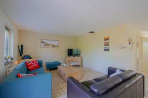 a living room with two blue couches and a tv at Noorderzon - Villaparc Duynopgangh Julianadorp aan Zee in De Zandloper
