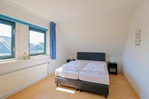 a bedroom with a bed and two windows at Noorderzon - Villaparc Duynopgangh Julianadorp aan Zee in De Zandloper