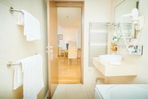 ein weißes Badezimmer mit Waschbecken und Spiegel in der Unterkunft ASTORIA Hotel Opatija in Opatija