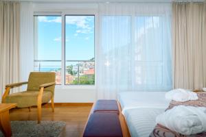ein Schlafzimmer mit zwei Betten und einem Stuhl und einem Fenster in der Unterkunft ASTORIA Hotel Opatija in Opatija