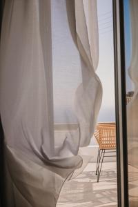 a window with a white curtain and a chair at Venue Villas - Folegandros in Áno Meriá