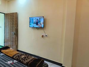 a flat screen tv on a wall with a couch at Kumkum guest house in Ujjain