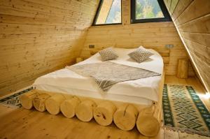 a bed in a log cabin with two windows at Cabana A Vis in Taşca