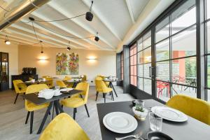 a restaurant with tables and yellow chairs and windows at Boutique Hotel Villa Cuserina wellness in Cannobio