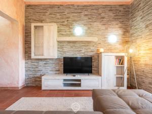 un salon avec une télévision sur un mur en briques dans l'établissement Blue Eden Vista, à Domus de Maria 30 autres photos