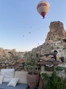 a hot air balloon flying over a village with a plant at Potamia Cave Suites in Ortahisar