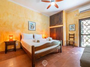 une chambre avec un lit et un ventilateur de plafond dans l'établissement Blue Eden Vista, à Domus de Maria