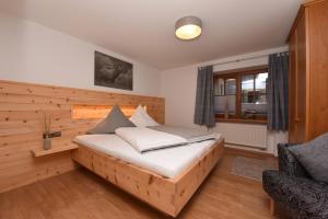 a bedroom with a bed with a wooden wall at Haus Bergheimat in Obermaiselstein