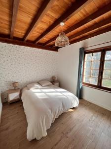 a bedroom with a large white bed and a wooden ceiling at La maison des bois à 10 minutes de Vezelay in Montillot