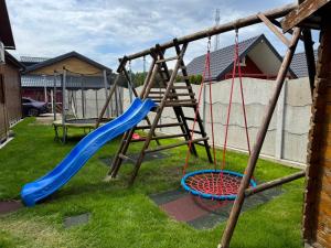 a playground with a blue slide and a swing at Domki Pajka in Międzyzdroje +19 photos