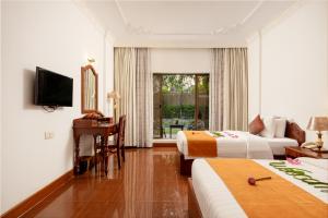 a hotel room with two beds and a desk and a television at YASODHARAPURA Residence in Siem Reap