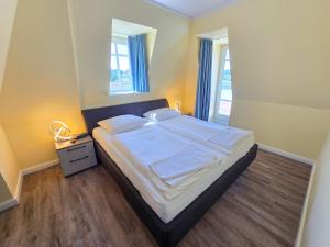 ein Schlafzimmer mit einem großen Bett mit weißer Bettwäsche in der Unterkunft Strandvillen Binz - Ferienwohnung mit Panoramablick, 2 Schlafzimmern und Balkon SV-715 in Binz