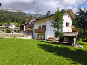 una casa bianca con un prato verde davanti di Ciasa Marta a Vigo di Fassa