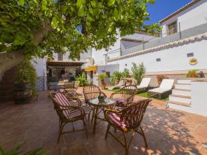 a patio with chairs and tables under a tree at Cubo's Noches de Luna Casabermeja House in Casabermeja