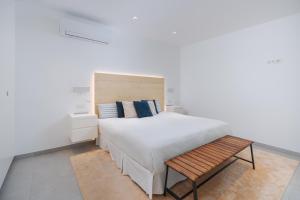 a bedroom with a bed and a wooden bench at Fahana Las Canteras in Las Palmas de Gran Canaria