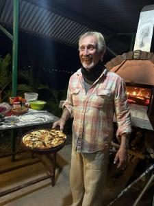 a man is holding a pizza on a table at Hotel Diplomat in Pokhara
