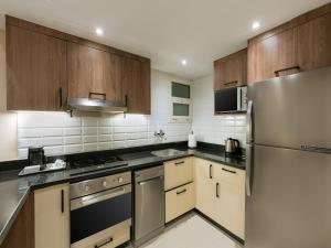 a kitchen with wooden cabinets and a stainless steel refrigerator at Second Home Hospitality, Rehab City, New Cairo, Cairo Egypt in New cairo