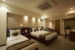 a hotel room with two beds and a couch at Metro Plaza Hotel in Mangalore