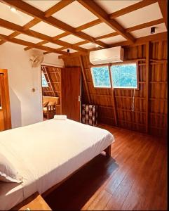 Schlafzimmer mit einem weißen Bett und Holzböden in der Unterkunft Hill View 'A'Frame Villa Wayanad in Vythiri