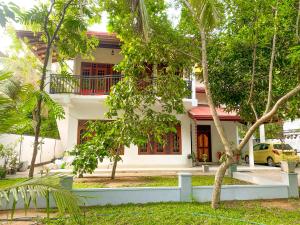 a white house with trees in front of it at Yala Safari Green Home Stay in Tissamaharama