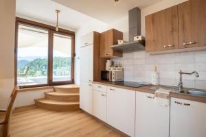kuchnia z białymi szafkami i dużym oknem w obiekcie Aparthotel Hom at Vintgar w mieście Zgornje Gorje