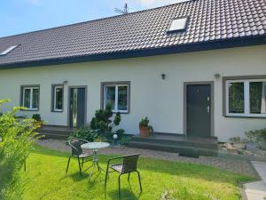 a house with chairs and a table in the yard at DW "Wrzosek" in Wrzosowo