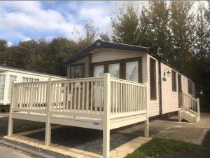 a small house with a porch and a deck at Haven Lakeland 3 Bed Luxury Caravan in Flookburgh
