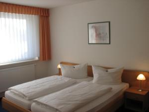 a bedroom with a bed with white sheets and pillows at Apartmenthotel-Harz in Friedrichsbrunn