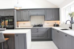 a kitchen with gray cabinets and white counter tops at Luxury holiday home with HOT TUB in St Merryn