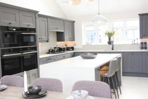 a kitchen with gray cabinets and a white counter top at Luxury holiday home with HOT TUB in St Merryn +13 photos