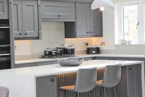 a kitchen with gray cabinets and a counter with chairs at Luxury holiday home with HOT TUB in St Merryn