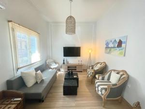 a living room with a couch and chairs and a tv at Stella's Petite Boîte in Rafina