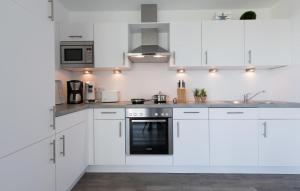 a white kitchen with white cabinets and a sink at Albatros in Olpenitz +12 photos