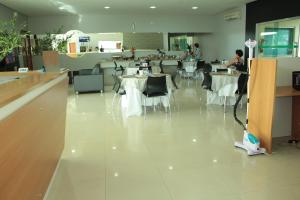 a restaurant with white tables and chairs and a room with people at Hotel Talissa 2 in Manaus