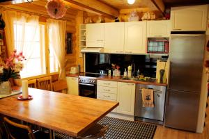 a kitchen with a wooden table and a stainless steel refrigerator at Kettu Holl Cottage in Taipalsaari
