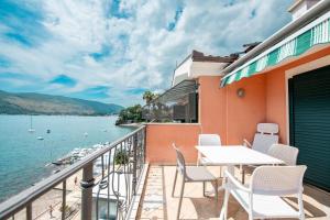 een balkon met een tafel en stoelen en uitzicht op het water bij Boka Apartment 1 in Herceg-Novi