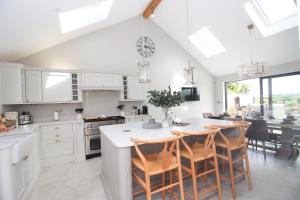 a kitchen with white cabinets and a table with chairs at Stylish home with HOT TUB in St Merryn