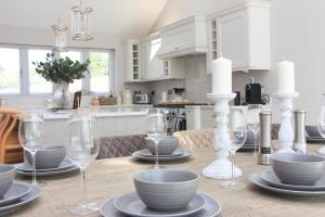 a table with plates and wine glasses on it at Stylish home with HOT TUB in St Merryn